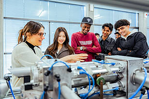 Studierende aus dem Bachelorstudiengang Mechanical Engineering schauen sich ein Maschinenteil an