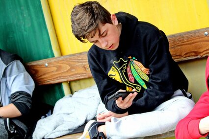 Junge sitzt und schaut auf sein Smartphone