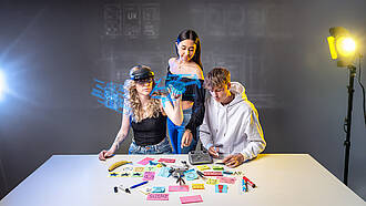 Drei Studierende des Studiengangs User Experience, die gemeinsam eine Drohne untersuchen..