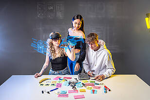 Drei Studierende des Studiengangs User Experience, die gemeinsam eine Drohne untersuchen..