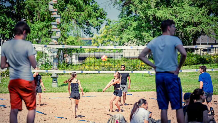Studierende spielen auf dem Beachvolleyballfeld der Beethovenstraße Volleyball.