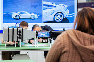 Zwei Studierende und ein Professor, des Bachelorstudiengangs Allgemeiner Maschinenbau arbeiten an einem Modell 