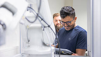 Zwei Studenten aus dem Bachelorstudiengang Mechatronics Engineering arbeiten an einem Roboter