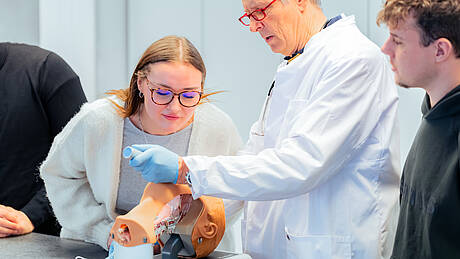 Professor zeigt Studierenden an einem Modell eine Intubation