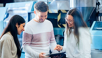 Studierende des Masterstudiengangs Leichtbau besprechen sich vor einer Maschine