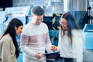 Studierende des Masterstudiengangs Leichtbau besprechen sich vor einer Maschine