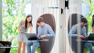 Zwei Studierende arbeiten gemeinsam an einem Laptop, in dem modernen Hochschulgebäude für Wirtschaft und Internationales (WIN).