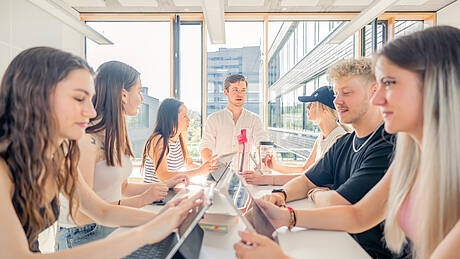Lernraum mit Studierendengruppe am Tisch mit Laptops