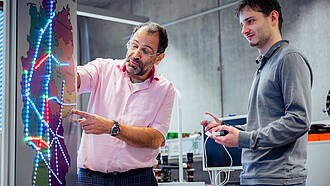 Professor des Masterstudiengangs Informatik erklärt einem Student etwas an einer Leuchttafel