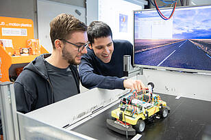 Zwei Studierende aus dem Masterstudiengang Mechatronik / Systems Engineering arbeiten an einer Fahrsimulation.