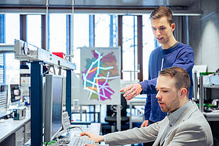 Zwei Studierende des Masterstudiengangs Machine Learning and Data Analytics unterhalten sich an einem PC