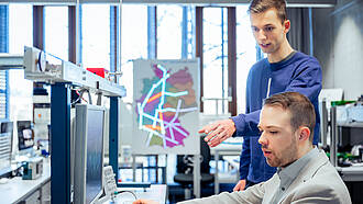 Zwei Studierende des Masterstudiengangs Machine Learning and Data Analytics unterhalten sich an einem PC