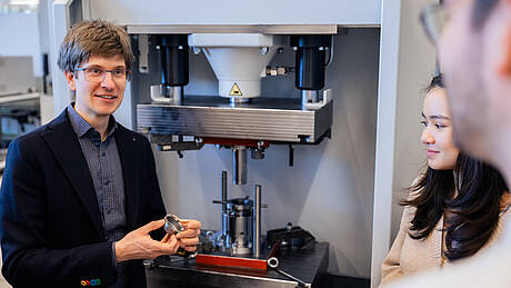 Professor und Studierende aus dem Masterstudiengang Produktentwicklung und Fertigung arbeiten an einer Maschine