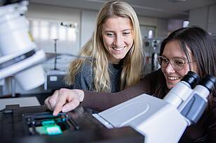 Zwei Studentinnen aus dem Masterstudiengang Applied Photonics arbeiten an einem Microskop 
