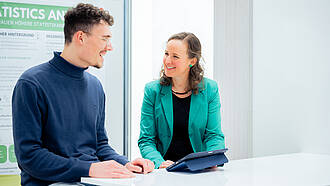 Eine Professorin spricht mit einem Studierenden des Masterstudiengangs Business Psychology and Sustainability