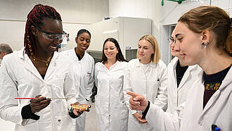 Sechs Studierende des Studiengangs Biopharmazeutische Wissenschaften untersuchen den Inhalt einer Petrischale.