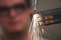 Foto: Ein Laborant arbeitet im Laserlabor an einem Werkstück