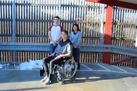 Fotografie: Eine Person mit Rollstuhl neben einer Rampe zu einem Gebäude