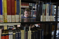 Foto: Person hinter Bücherregal in Bibliothek