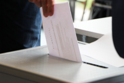 Foto: Person wirft Wahlunterlagen in Urne
