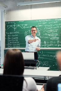 Foto: Ein Professor steht vor einer Tafel und spricht mit seinen Dozenten