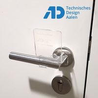 Foto: Eine Klinke mit einer Plastik Applikation, die das Öffnen der Tür nur mit dem Unterarm ermöglicht