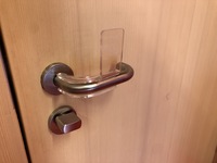 Foto: Eine Klinke mit einer Plastik Applikation, die das öffnen der Tür nur mit dem Unterarm ermöglicht