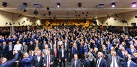 Foto: Ein Saal voller Absolventen. Sie werfen ihre Bachelormützen in die Höhe