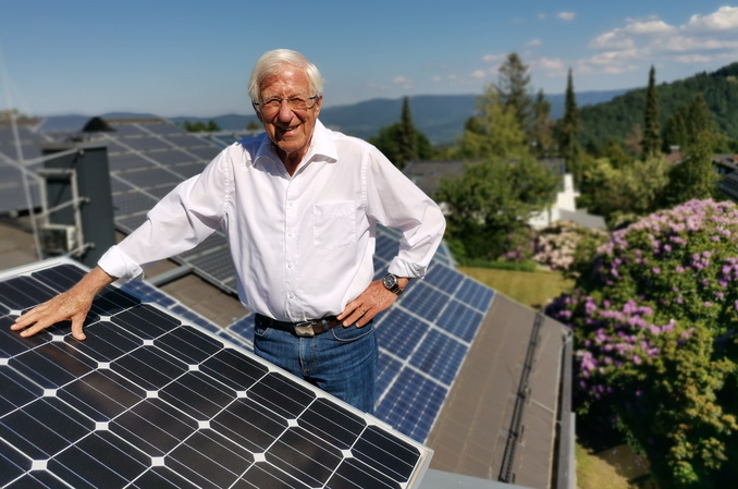 Foto: Mann mit Sonalpanelen auf einem Dach im Sonnenschein