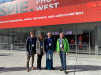 Vier Personen stehen vor dem "Photonics West 2023"-Gebäude in San Francisco.